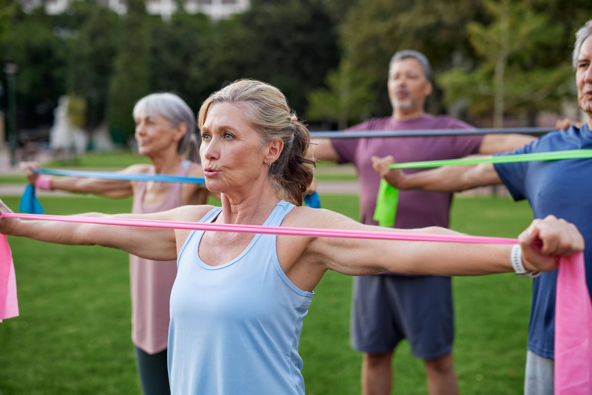 Persone mature che si esercitano con la fascia di resistenza al parco